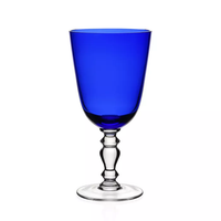 The William Yeoward Fanny Colored Country Goblet 13 oz. features vibrant cobalt blue glass with a clear, ornate stem and round base—an elegant addition to any table setting, shown here against a white background.