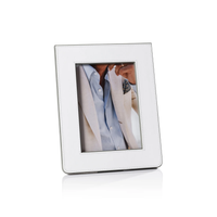 The Zodax Napoli Leather Frame White & Grey displays a photo of a person in a light beige suit jacket, blue shirt, and patterned pocket square. The elegant frame stands upright against a white background, enhancing any space.