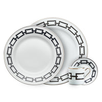 The Ginori 1735 Catene Nero Dinnerware set features two plates of different sizes and a small cup with matching saucer, all adorned with a distinctive black and gold chain-link geometric border.