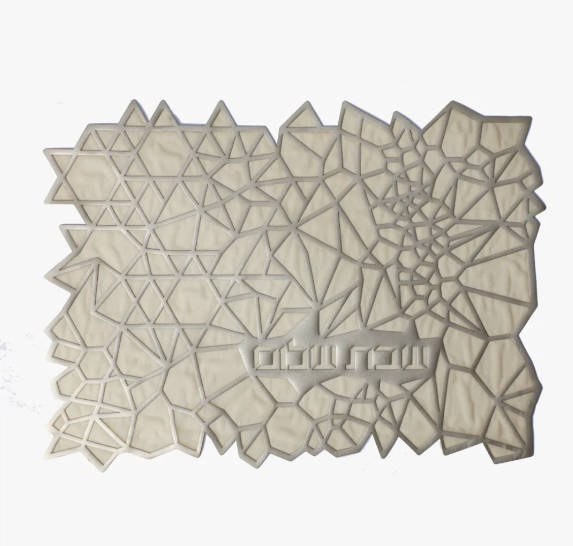 The Apeloig Geometric Challah Cover features an abstract design with interconnected triangles and polygons in white and light gray, Hebrew text, and an irregular mosaic pattern—perfect as a modern or unique laser-cut challah cover.