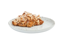 A flaky almond croissant topped with sliced almonds and powdered sugar, served on Blue Pheasant’s Marcus Dinnerware - White Salt Glaze - Set of 4, displayed against a white background.