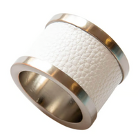 The Von Gern Home Zinc & Leather Napkin Ring S/4 features a wide metallic design with shiny gold edges and a textured white leather center, displayed against a white background.