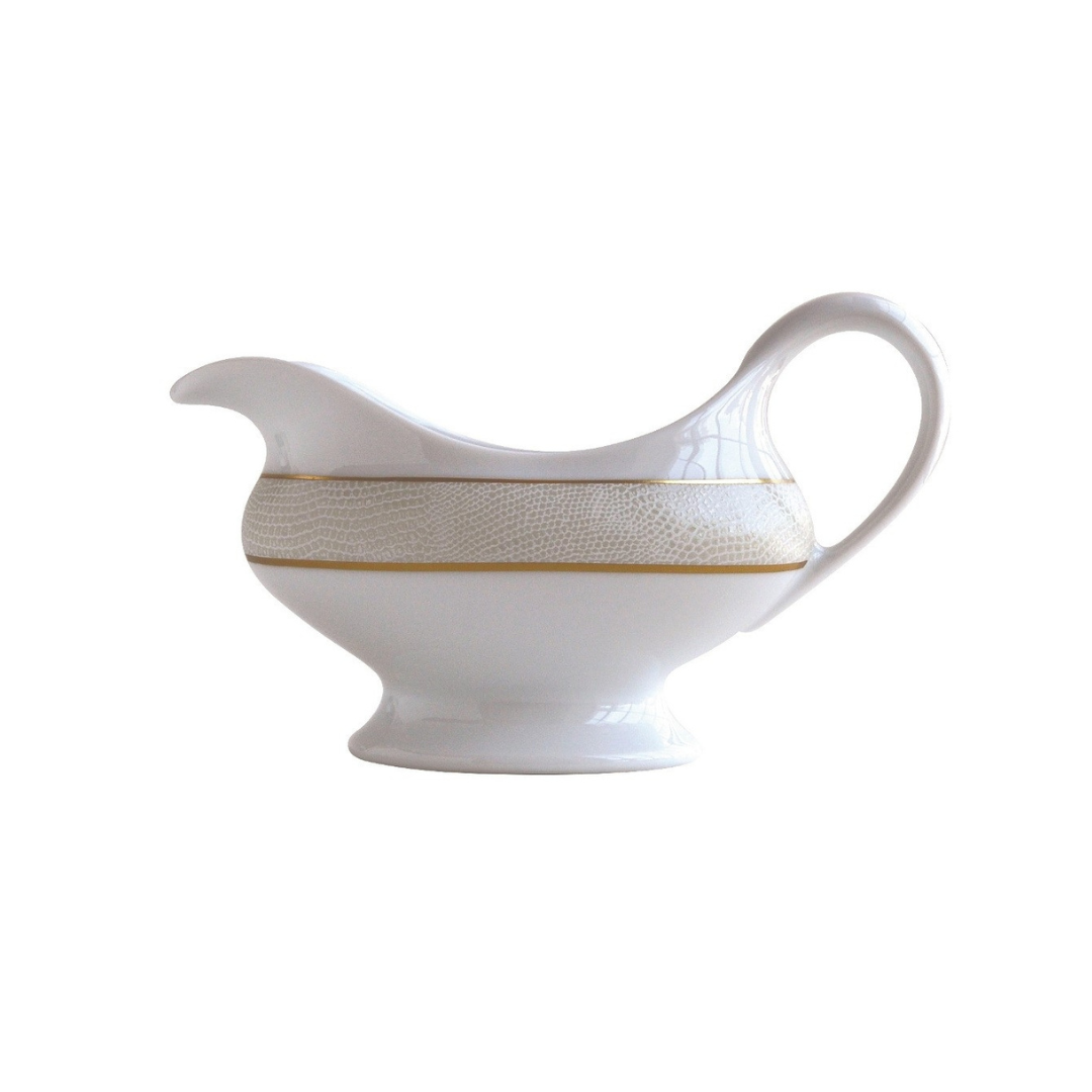 The Sauvage Gold Dinnerware gravy boat by Bernardaud features white Limoges porcelain, an embossed beige snake-skin-textured band, and elegant gold trim.