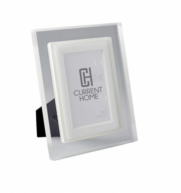 The Prisma Frame Lip - Eggshell by Bella Moulding is a white and silver freestanding acrylic photo frame with a black stand, offering modern protection and elegant display for your 5x7 photos.
