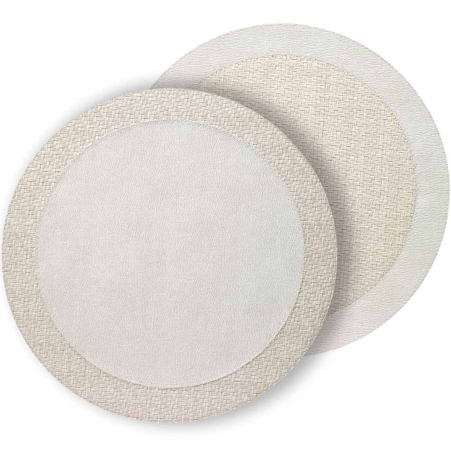 Two round Bodrum Halo placemats from the Neutrals set overlap, each reversible with a plain center and woven-pattern border—one in light beige, one in off-white—perfect for modern tables. Set includes 4 placemats.