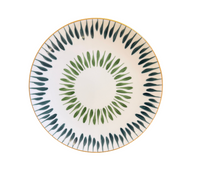 The Marie Daâge Allee de Cypres 5 by Marie Daâge is a round white plate with a gold rim, expertly crafted from exquisite Limoges porcelain. Hand painted with two circular patterns of green and dark teal leaf motifs radiating from the center, this luxurious French dinnerware piece brings refined elegance to any dining experience.