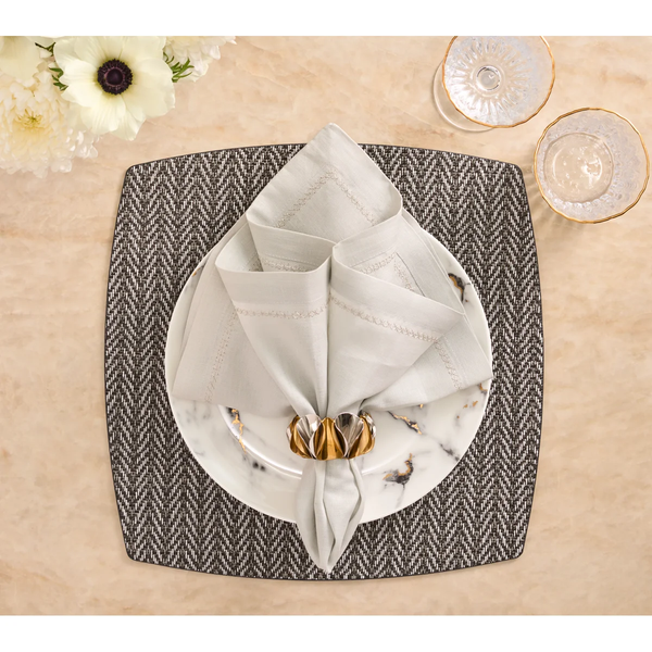 White plate with a folded napkin and gold-toned napkin ring centered on a black and white Twill Placemat Set of 4 - Black & White.