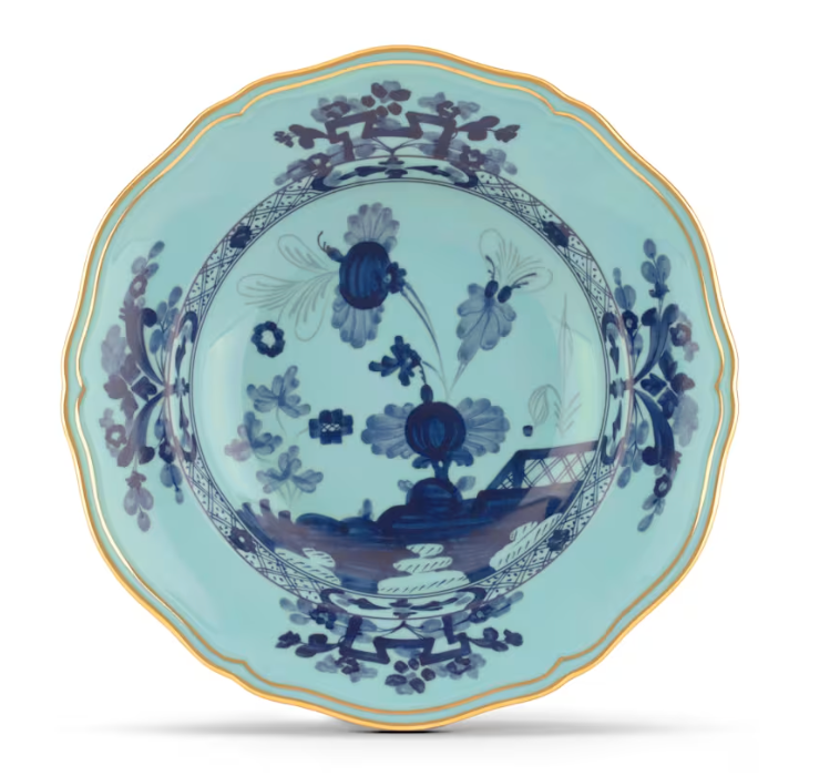 The Oriente Italiano Dinnerware Iris by Ginori 1735 features a scalloped edge with gold rim, a light blue background, and dark blue chinoiserie floral motifs at the center and border.