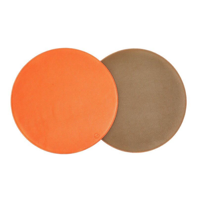 Four reversible placemats by Von Gern Home, shown in bright orange and tan, are arranged side-by-side on a white background for an elegant table setting.