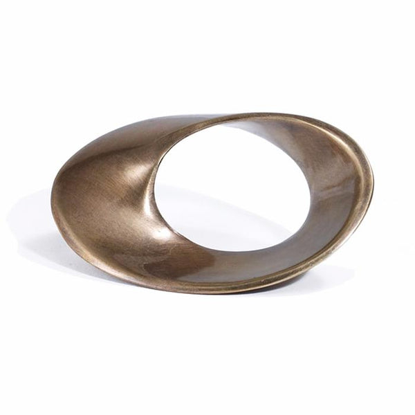 A bronze, abstract, hollow sculpture with a smooth, curved, asymmetrical form resembles an oversized Morgan Napkin Ring s/4 Bronze by Bodrum and rests on a white surface.
