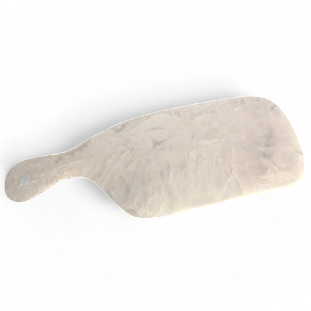 The Arila Cheese Board - White Swirl by Nashi Home is a rectangular cheese board with a marble-textured finish, rounded edges, and a handle with a small hanging hole. Hand-crafted from shatterproof resin, it’s perfect for outdoor entertaining and is shown here on a white background.
