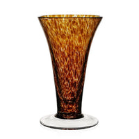 The Vanessa Vase - Tortoise by William Yeoward is a tall, flared glass vase with a wide base, narrow neck, and a mottled amber-brown pattern. Its clear base contrasts beautifully with the richly textured Mediterranean-inspired design.