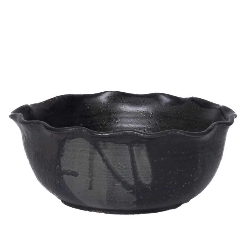 The Leona Bowl - Marina by CDMX / MASA TALLER is a black ceramic serving bowl featuring a wavy, scalloped rim and a subtly textured surface. Set against a plain white background, this piece makes an elegant and striking decorative accent for any setting.