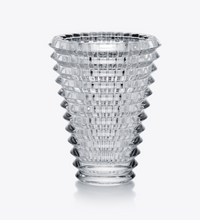 The Baccarat Eye Oval Vase is a clear, textured crystal piece with a wide top and narrow base, showcasing a geometric pattern of layered horizontal and vertical bevel cuts.
