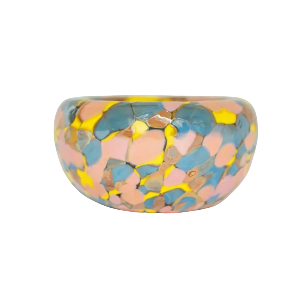 Introducing the Jelly Baby Bubble Bowl ring by Maria Ida Designs—a round, chunky piece with a glossy finish, showcasing an abstract pattern of yellow, blue, and pink patches reminiscent of the vibrant artistry found in blown glass bowls and art glass creations.