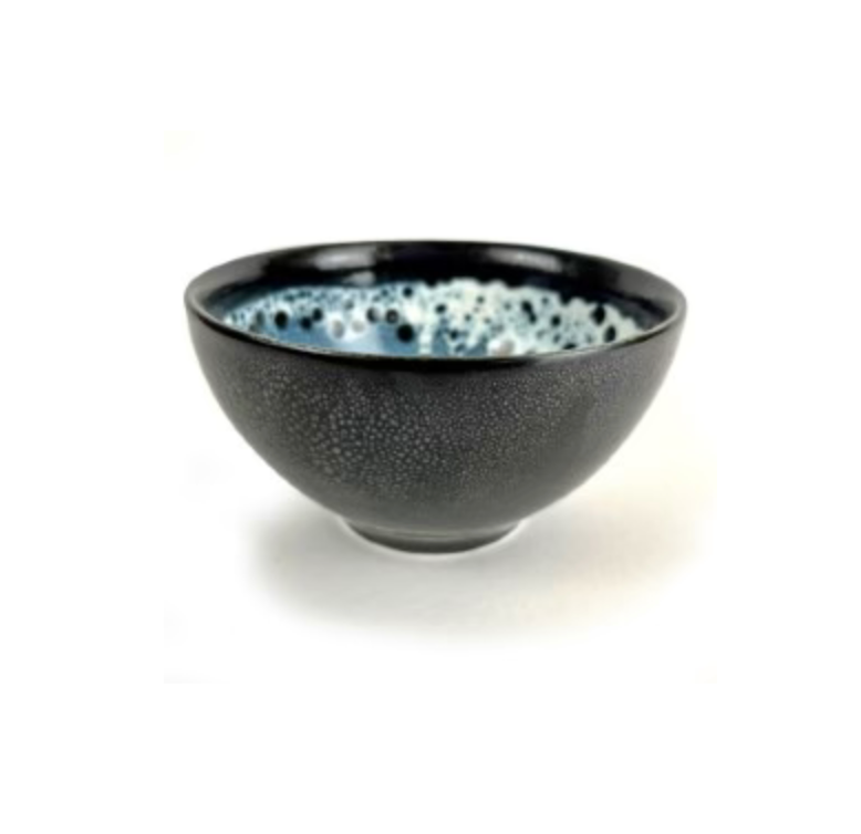 The Wabi Dip Bowl by Michael Wainwright features a dark, textured exterior with a glossy, speckled blue and white interior, shown against a plain white background.