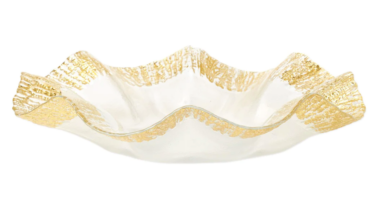 The Vietri Rufolo Glass Dinnerware Gold is a clear glass bowl with wavy, ruffled edges and gold accents along the rim, pairing beautifully with Italian style dinnerware.