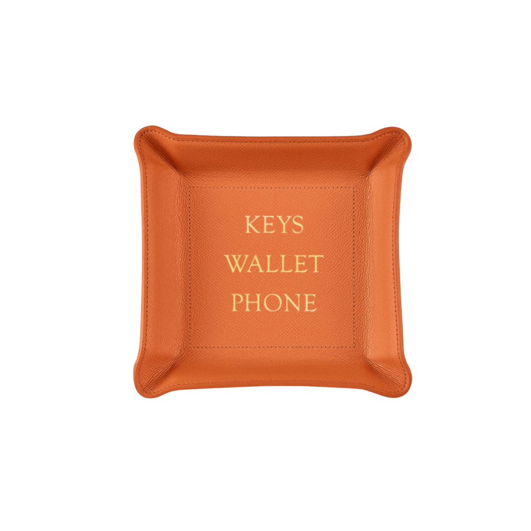 The Graphic Image Leather Valet Tray - Keys Wallet Phone is a square orange leather catchall with "KEYS WALLET PHONE" embossed in yellow at the center, featuring curved edges—ideal as a stylish travel organizer.