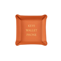The Graphic Image Leather Valet Tray - Keys Wallet Phone is a square orange leather catchall with "KEYS WALLET PHONE" embossed in yellow at the center, featuring curved edges—ideal as a stylish travel organizer.