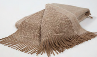 The Coco Throw by Mantas Ezcaray is a luxurious double-sided blanket in beige and brown Chanel fabric, featuring fringed edges and elegantly displayed on a white background.