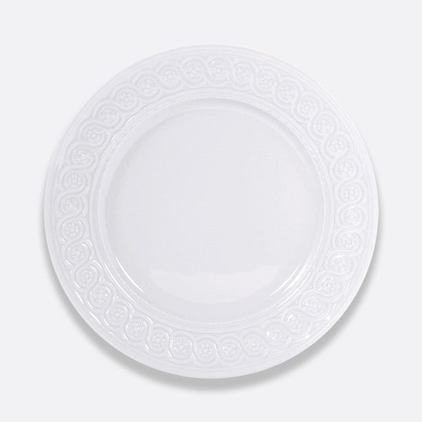 The Louvre Dinnerware by Bernardaud is a round, white ceramic plate featuring an ornate, Renaissance-inspired embossed border, showcased against a plain light gray background.