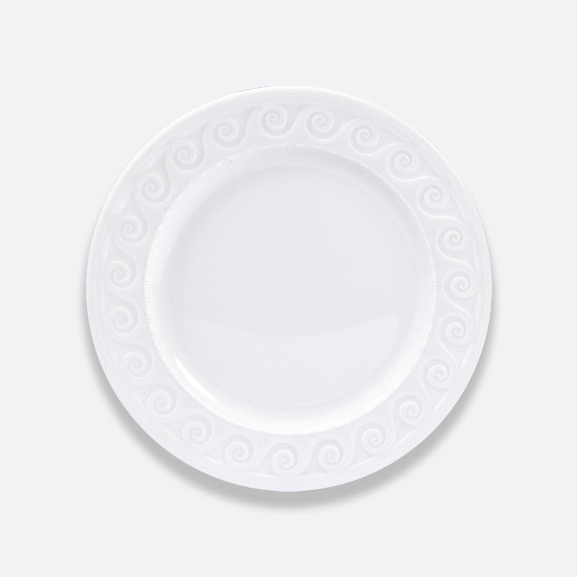 The Louvre Dinnerware by Bernardaud is a plain white ceramic plate featuring a decorative swirl pattern inspired by Renaissance French architecture, shown from above on a light gray background.