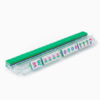 The Oh My Mahjong Mahjong Tiles Set - Jasmine includes a clear plastic tile rack that displays green Jasmine tiles at the back and colorful acrylic tiles with symbols and numbers at the front, ideal for an engaging mahjong game.