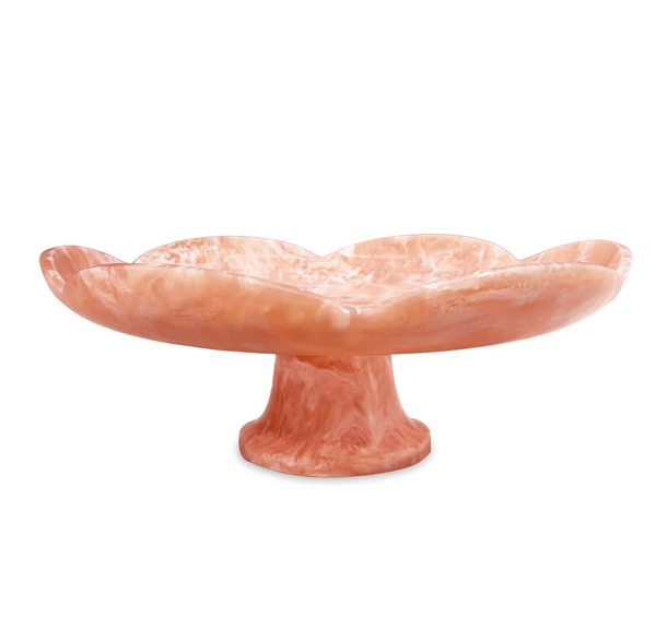 The Beatriz Ball Resin Amelia Pedestal Cake Plate in peach features a marble pattern, scalloped flower-like edge, and wide shallow dish—perfect as a handcrafted tableware accent or serving platter.