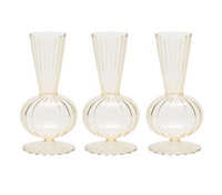 Four identical champagne-colored glass bud vases from Kim Seybert's Tess Bud Vase Set, featuring vertical ribbed patterns, rounded bases, and fluted edges, are arranged in a row against a white background.