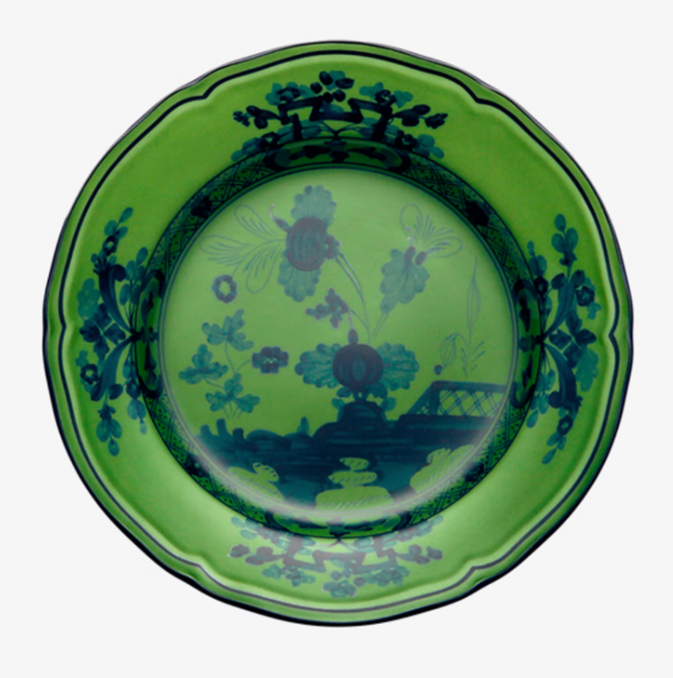The Oriente Italiano Dinnerware Malachite by Ginori 1735 is a round, green ceramic plate with a wavy edge, adorned with a dark blue floral and landscape pattern on the rim and center.