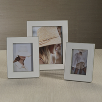 Three Zodax Napoli Leather Frames in white and grey rest on a light-colored surface, each displaying a stylish fashion photo of women in neutral outfits and hats against soft, muted backgrounds.