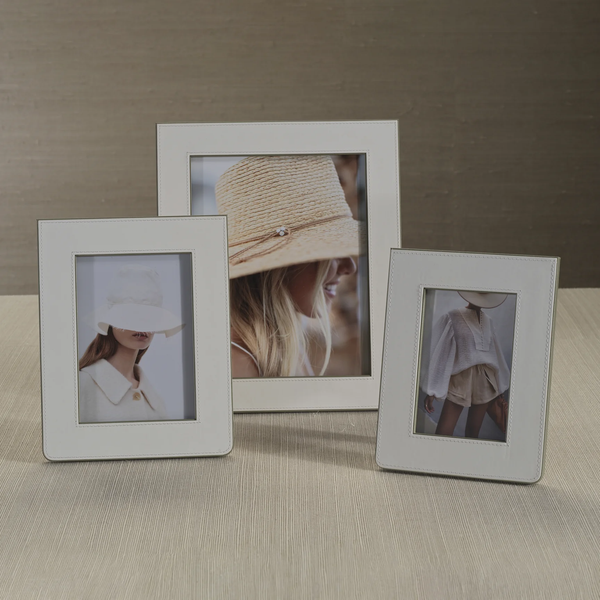Three Zodax Napoli Leather Frames in white and grey rest on a light-colored surface, each displaying a stylish fashion photo of women in neutral outfits and hats against soft, muted backgrounds.