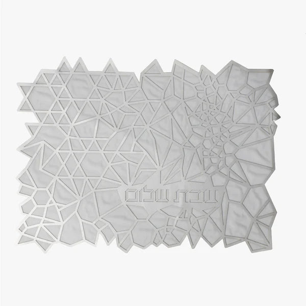 The Geometric Challah Cover by Apeloig is a modern white cover with an abstract pattern of polygons and triangles, featuring Hebrew text on the lower right.