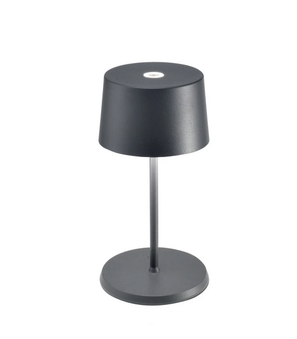 The Zafferano Olivia Mini Table Lamp features a modern, minimalist design in dark grey, with a conical shade, slim stem, and round base. It’s rechargeable and cordless.