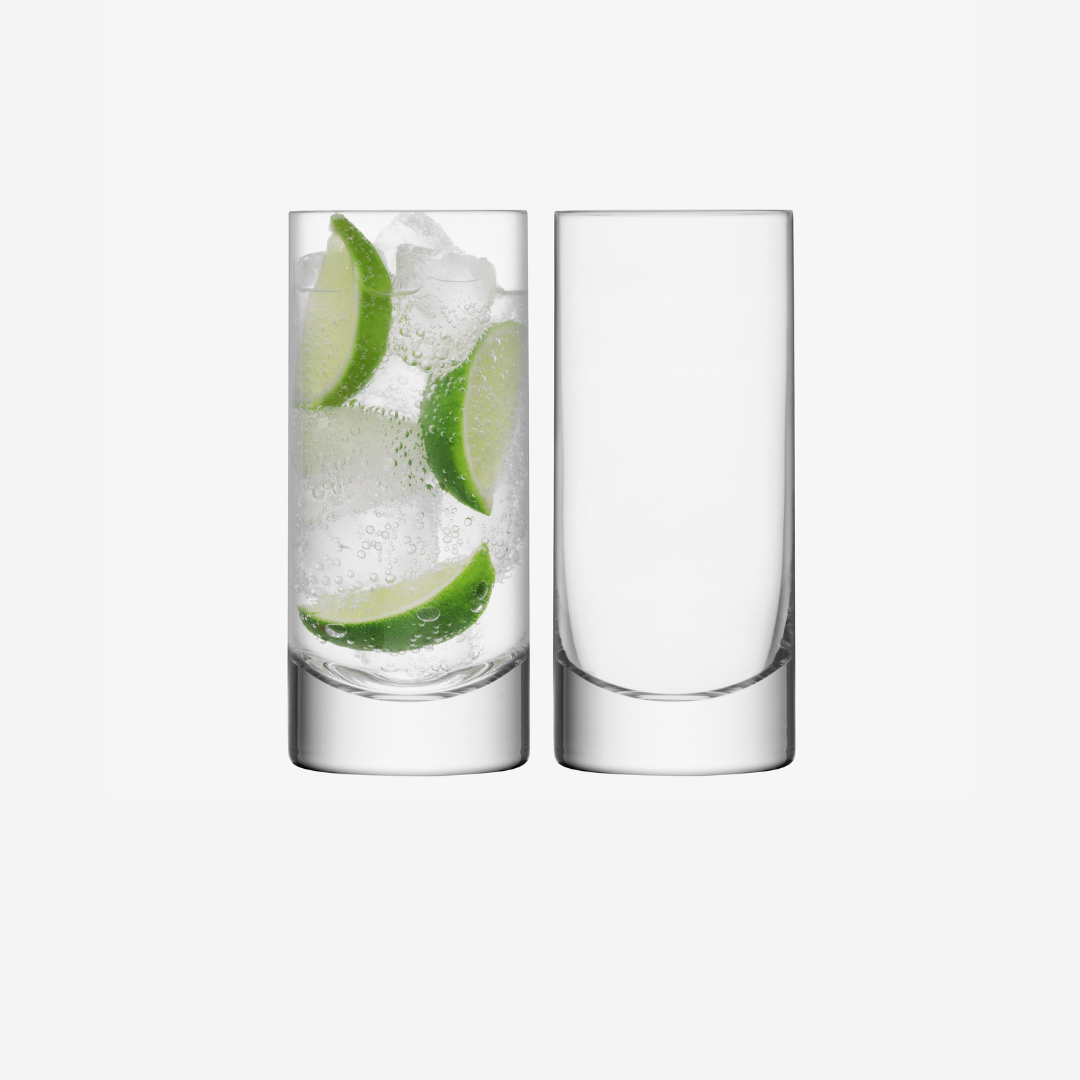 Two clear, tall LSA Bar Drinkware glasses are side by side on a plain white background; one holds sparkling water with ice and lime, the other is empty.