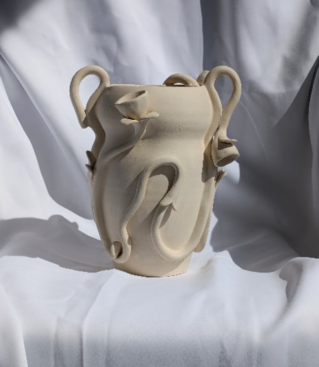 The Floral Vase by Terroso Studios is a beige handmade piece with abstract, swirling, snake-like handles, photographed against a draped white fabric background.