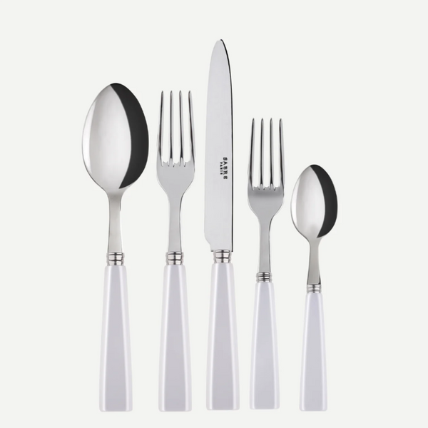 The Sabre Icone 5pps w/ Serrated Knife by Sabre features five stainless steel utensils with white handles—tablespoon, serrated dinner knife, dinner fork, salad fork, and teaspoon—arranged side by side on a white background; all are dishwasher safe.