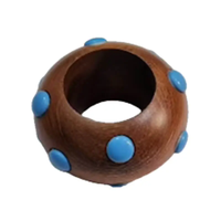 This smooth, round wooden bangle bracelet is adorned with evenly spaced blue studs, echoing the playful design of Von Gern Home's Candy Dots Napkin Ring Set of 4.