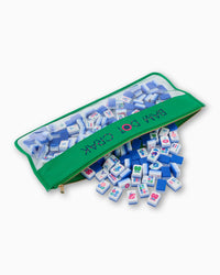 A green Oh My Mahjong Mahjong Tile Bag with a clear window holds tiles, some of which have fallen out and are scattered on a white background.