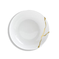 A piece from Bernardaud’s Kintsugi Dinnerware collection, this white ceramic plate features gold lines reminiscent of repaired cracks, drawing inspiration from the Japanese art of Kintsugi, and is displayed against a white background.