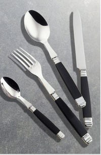 The Alain Saint-Joanis Empire Black Flatware 5 Piece Setting features stainless steel heads and sleek black handles, including a spoon, fork, knife, and teaspoon, stylishly displayed on a gray stone surface.