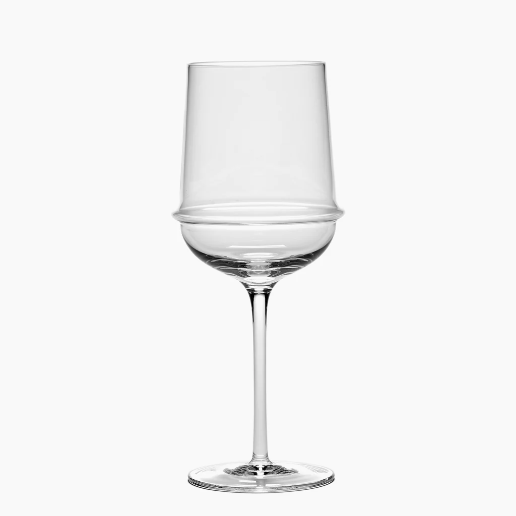 The Dune White Wine Glass by Serax features a clear, modern design with an angular bowl and a distinctive horizontal ridge encircling the middle. This artisanal glass is finished with a long, slender stem and rests on a flat base, shown here against a white background.