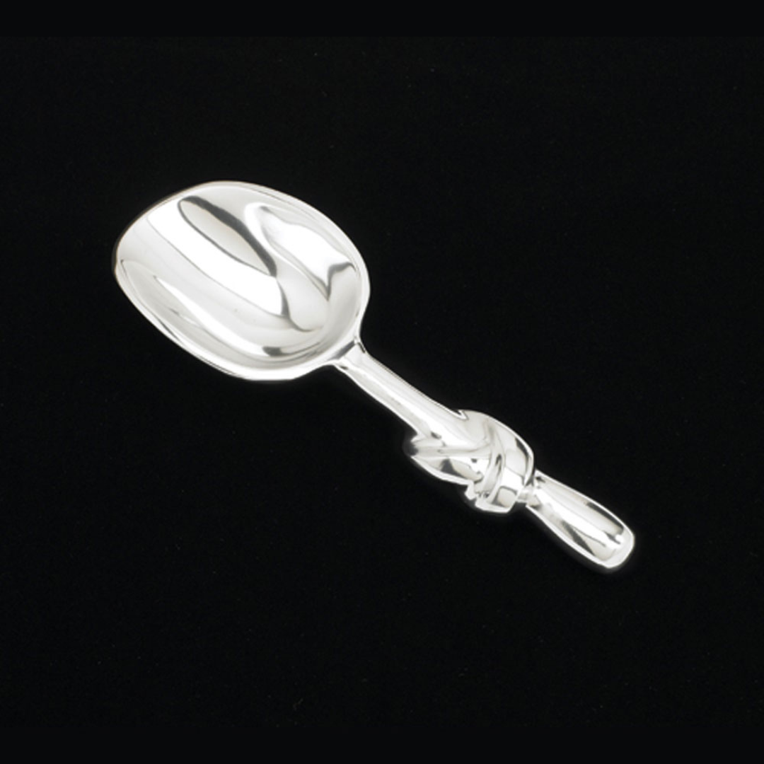 The Inspired Generations Knotty Scoop, crafted from food-safe aluminum with a decorative handle and shiny silver finish, is showcased against a solid black background.