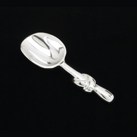 The Inspired Generations Knotty Scoop, crafted from food-safe aluminum with a decorative handle and shiny silver finish, is showcased against a solid black background.