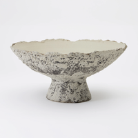 The Joelle Bowl by Dumae features a textured, footed design with a wide, flared rim. Its mottled gray and white exterior has a Sierra finish, while the smooth off-white interior highlights expert hand-crafted ceramic artistry.