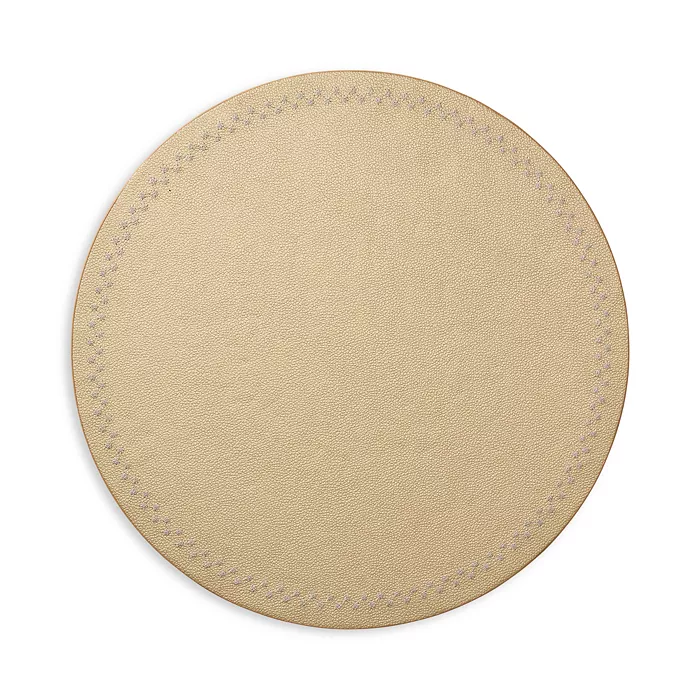 A set of four round, beige leather Starry Night Placemats by Kim Seybert, featuring subtle edge stitching and an easy-to-clean design, displayed against a white background.