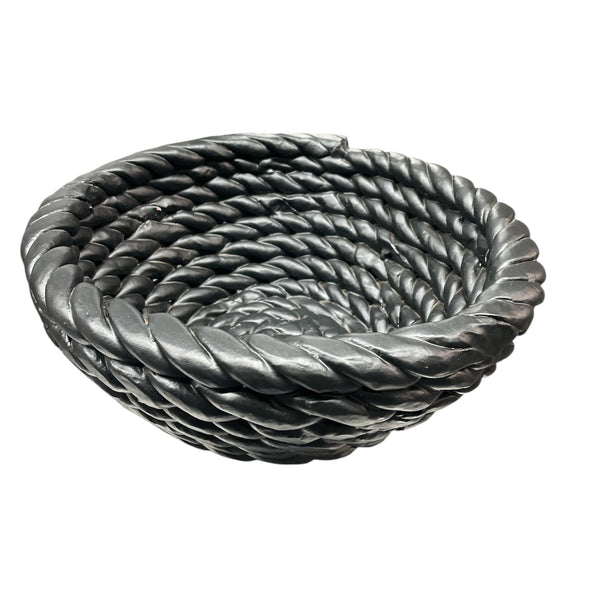 The Tissit Bowl Matte Black by Schwung Design is a round ceramic piece with a thick twisted rope spiral design, matte black finish, and smooth texture—serving as a striking modern accent against a white backdrop.