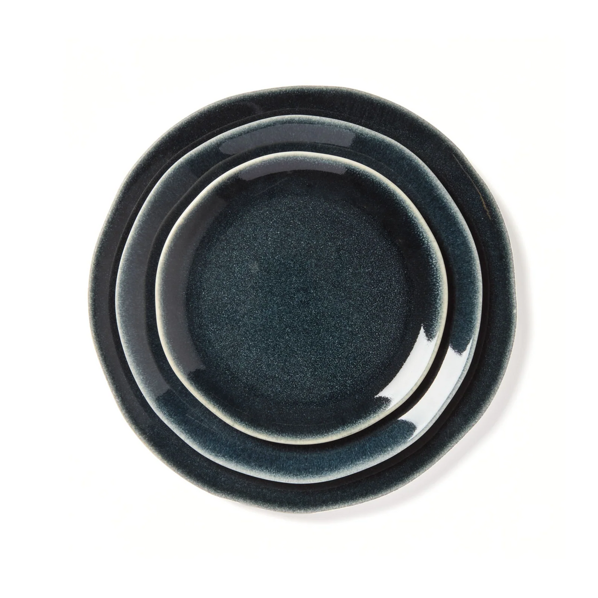 Three Maguelone Midnight Blue Dinnerware plates by Jars - Rosenthal, in varying sizes, are stacked on a white background, smallest on top and largest on bottom—ideal for showcasing artisanal craftsmanship.