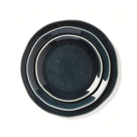 Three Maguelone Midnight Blue Dinnerware plates by Jars - Rosenthal, in varying sizes, are stacked on a white background, smallest on top and largest on bottom—ideal for showcasing artisanal craftsmanship.