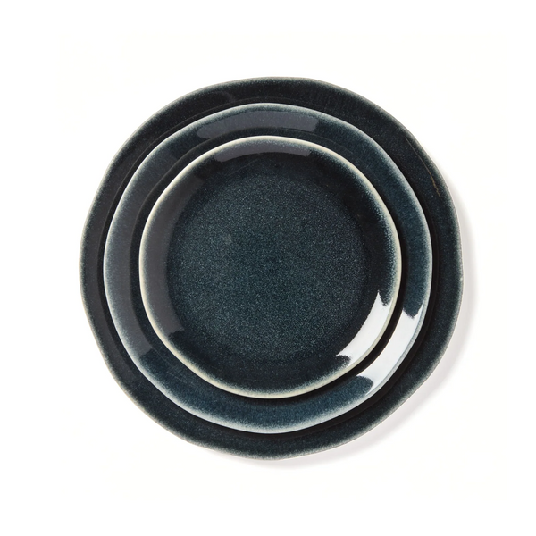 Three Maguelone Midnight Blue Dinnerware plates by Jars - Rosenthal, in varying sizes, are stacked on a white background, smallest on top and largest on bottom—ideal for showcasing artisanal craftsmanship.
